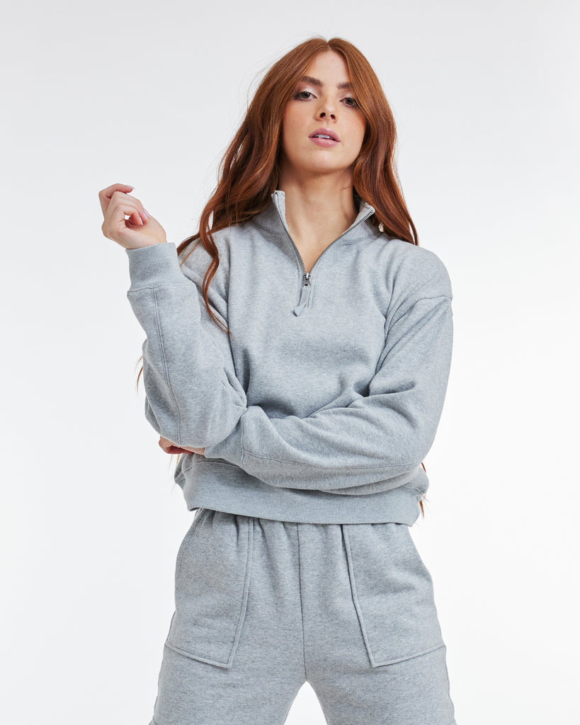Woman in a gray, long sleeve, quarter zip sweatshirt
