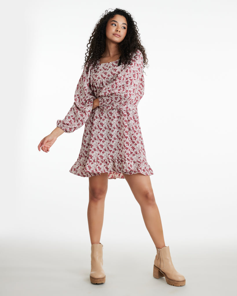 Woman in a red floral print, long sleeve, mini-length dress