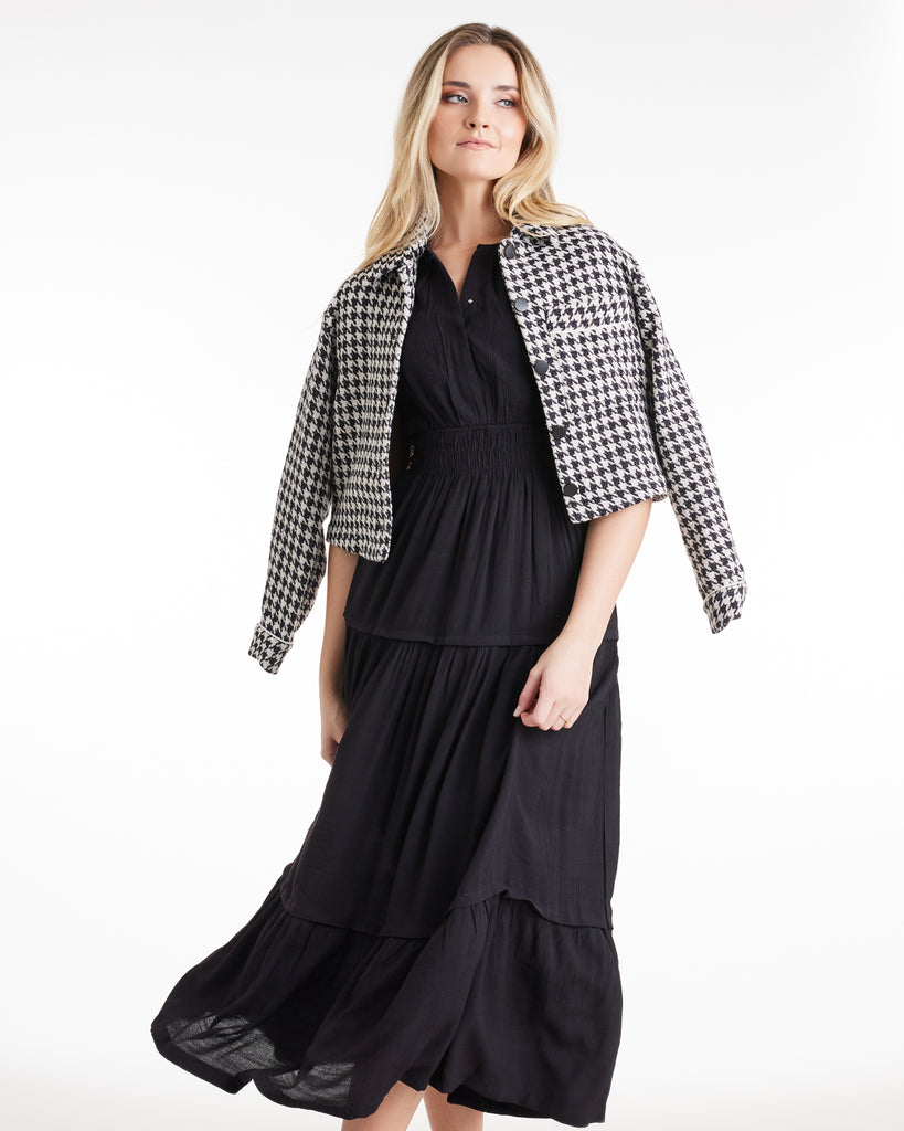 Woman in a black and white houndstooth, long sleeve, collared jacket