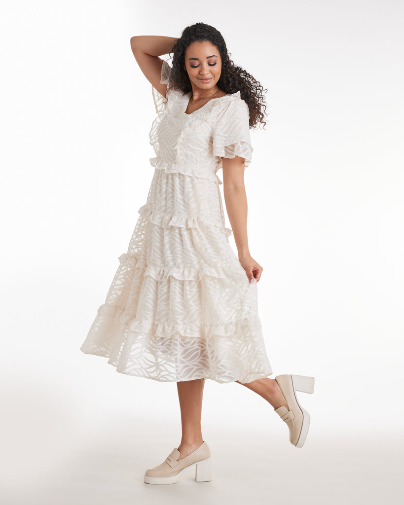 Woman in a short sleeve, tiered ruffle skirt dress in white