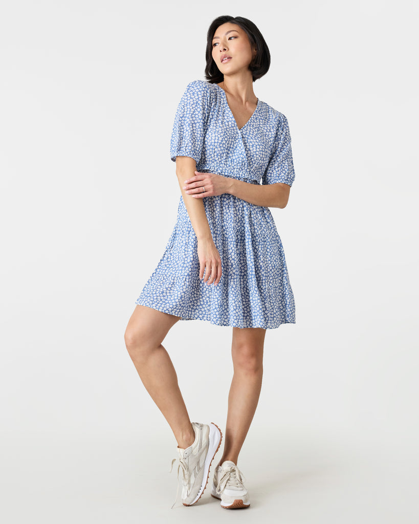 Woman in a short sleeve, mini dress that is blue and white with a v-neckline