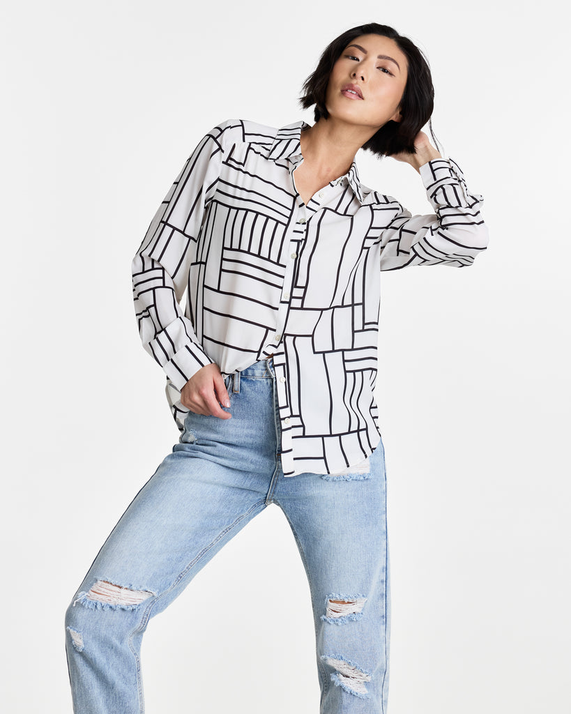 Woman in a black and white geometric printed, long sleeve, buttondown blouse