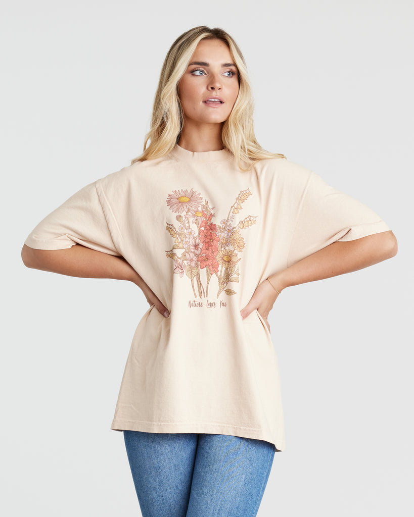 Woman in a pink short sleeve graphic t-shirt with flowers on the front