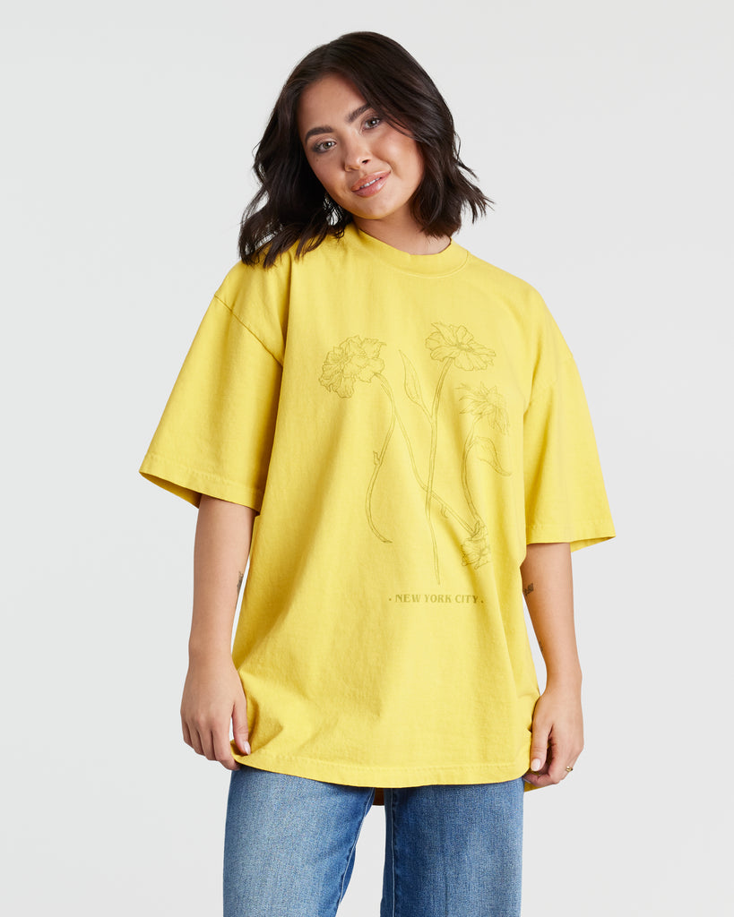 Woman in a yellow short sleeve graphic t-shirt with flowers on the front