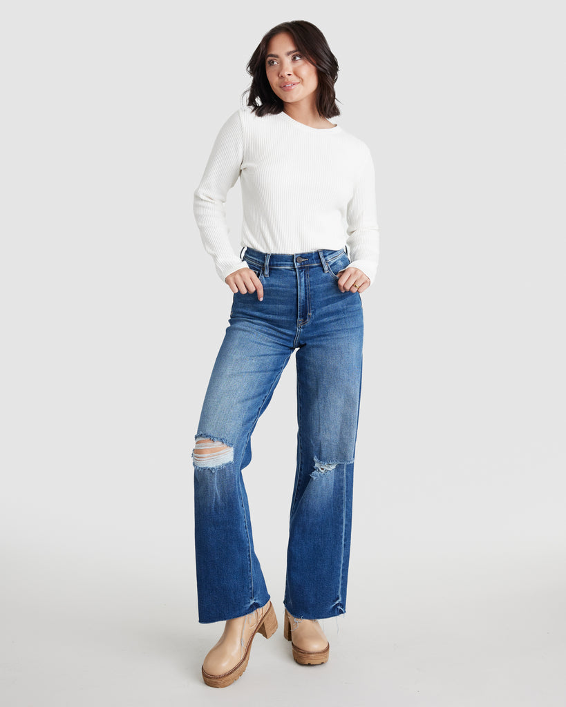 Woman in blue denim, ankle length jeans with tears on both knees
