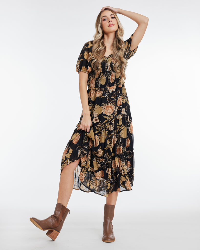 Woman in a tan and black floral print, short sleeve, midi dress