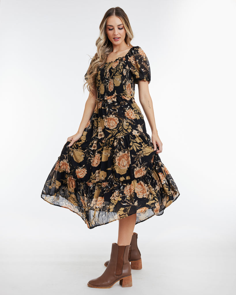 Woman in a tan and black floral print, short sleeve, midi dress