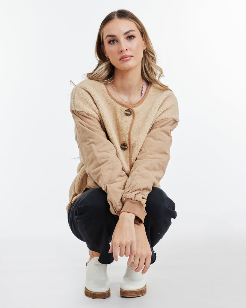 Woman in a tan, long sleeve, quiled jacket