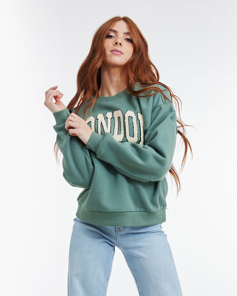 Woman in a green long sleeve sweatshirt with "LONDON" across the front