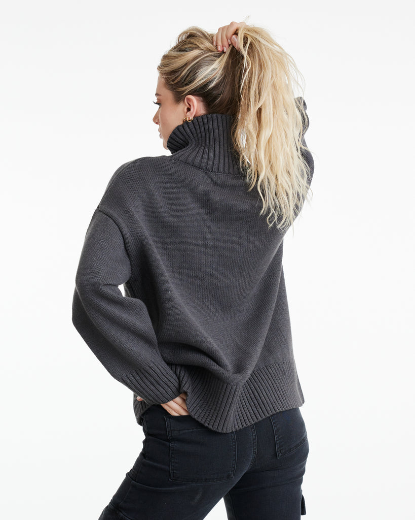 Woman in a charcoal, long sleeve turtleneck sweater