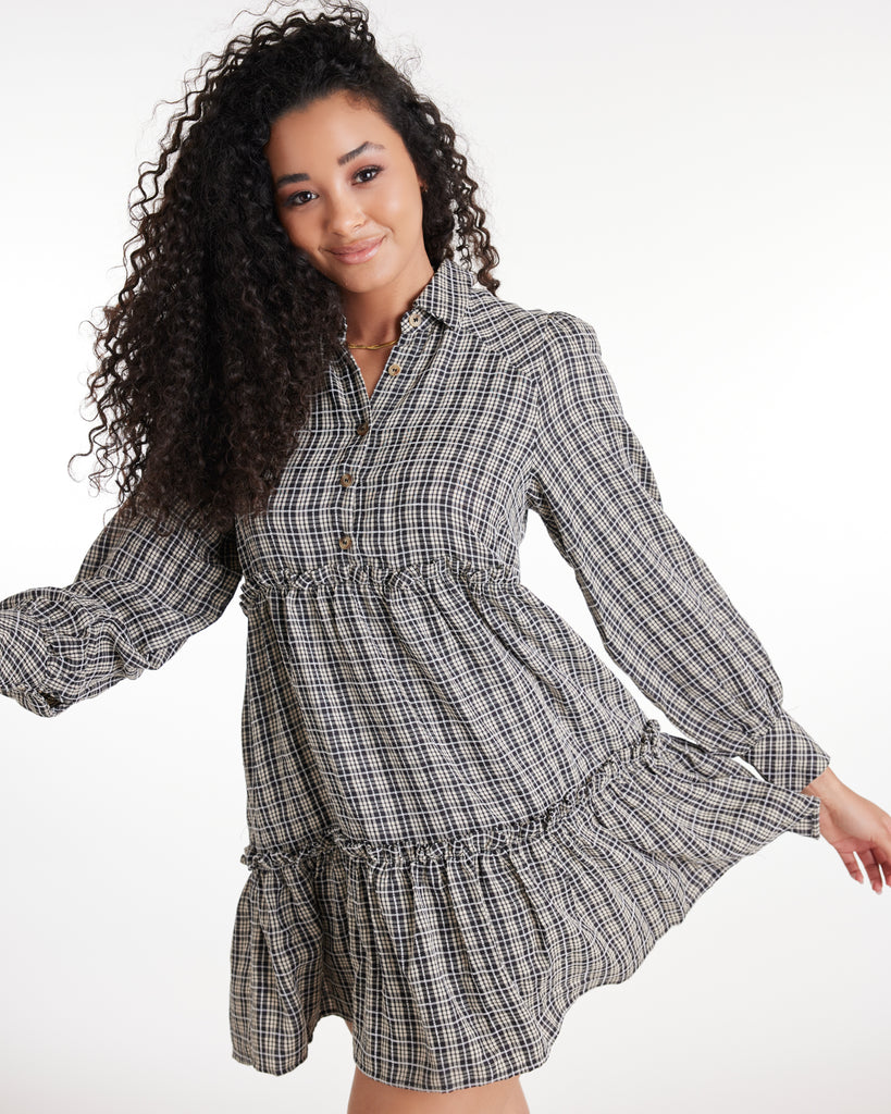 Woman in a plaid long sleeve, collared, mini-length dress