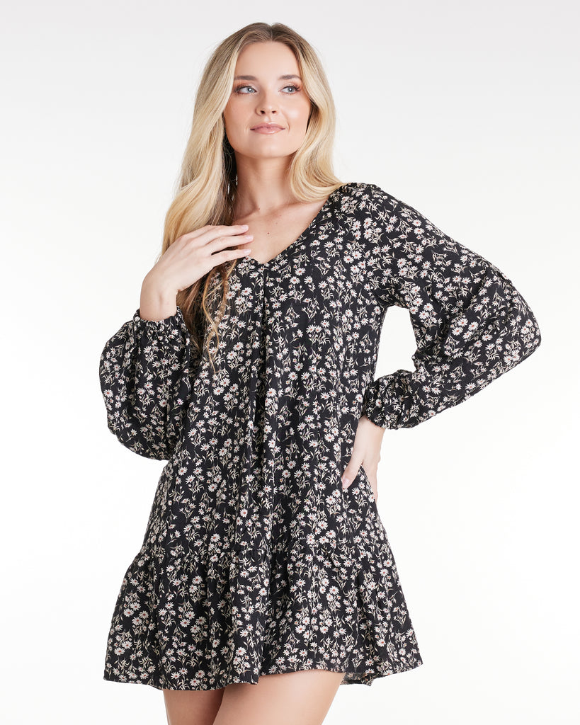 Woman in a long sleeve, black and gray floral print, mini dress