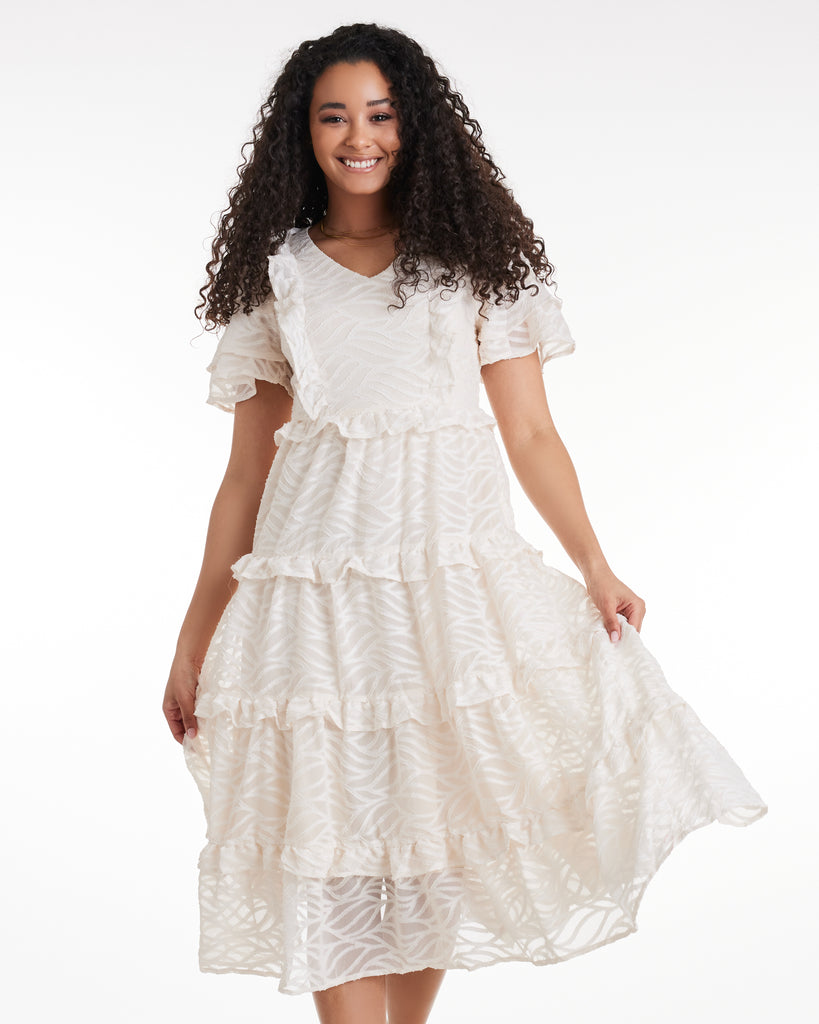 Woman in a short sleeve, tiered ruffle skirt dress in white