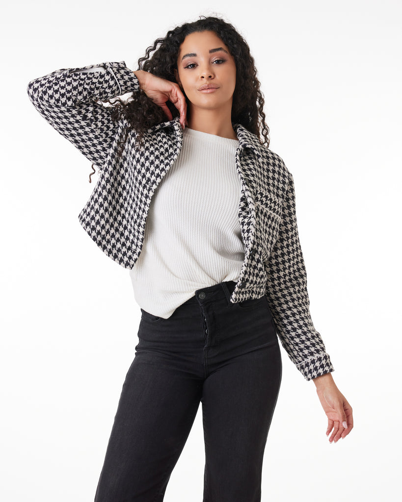 Woman in a black and white houndstooth, long sleeve, collared jacket