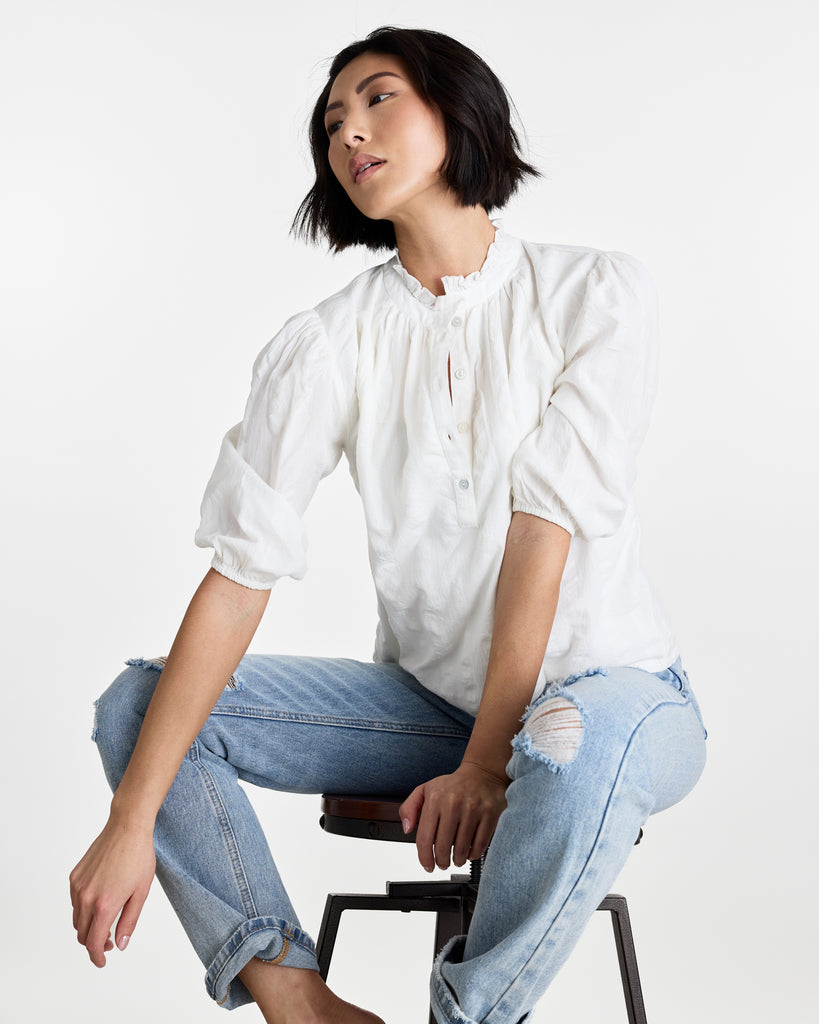 Woman in a white, half sleeved, mock-neck blouse