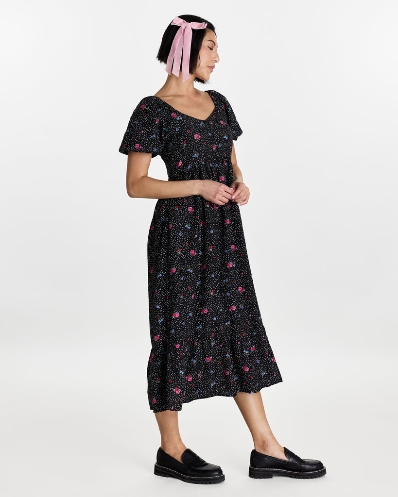 Woman in a short puffed sleeve, midi-length, black with floral print dress